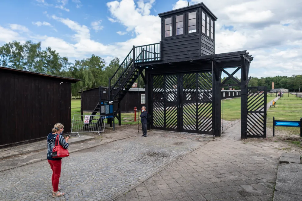 Pessoas em frente ao chamado 'Portão da Morte' enquanto visitam o museu no antigo campo de extermínio nazista de Stutthof, em Sztutowo, Polônia, 21 de julho de 2020. (Wojtek RADWANSKI / AFP)