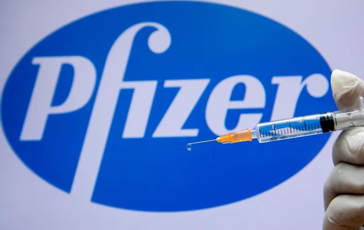 Olivier Fitoussi / Flash90 Um trabalhador médico israelense segurando uma seringa com a vacina contra o coronavírus ao lado do logotipo da empresa Pfizer em Jerusalém em 10 de dezembro de 2020.