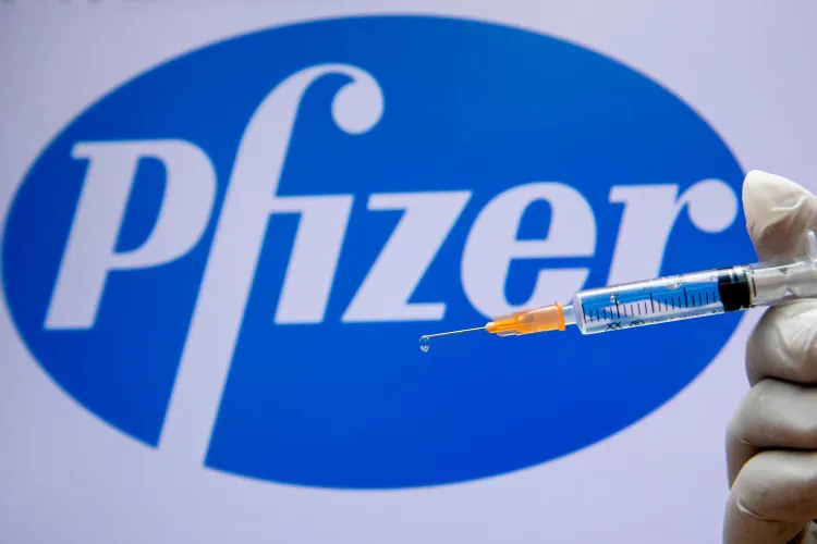 Olivier Fitoussi / Flash90 Um trabalhador médico israelense segurando uma seringa com a vacina contra o coronavírus ao lado do logotipo da empresa Pfizer em Jerusalém em 10 de dezembro de 2020.