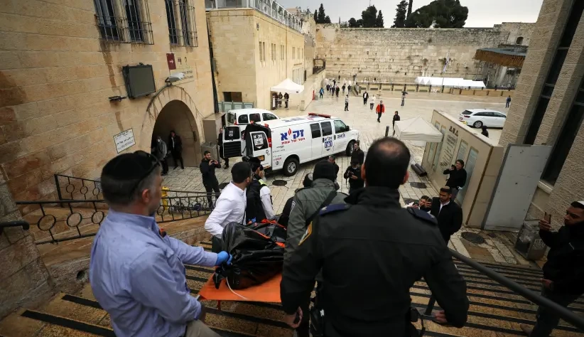 O pessoal de segurança israelense carrega um cadáver descendo as escadas que levam ao Muro das Lamentações, após um tiroteio na Cidade Velha de Jerusalém. (crédito da foto: REUTERS / AMMAR AWAD)