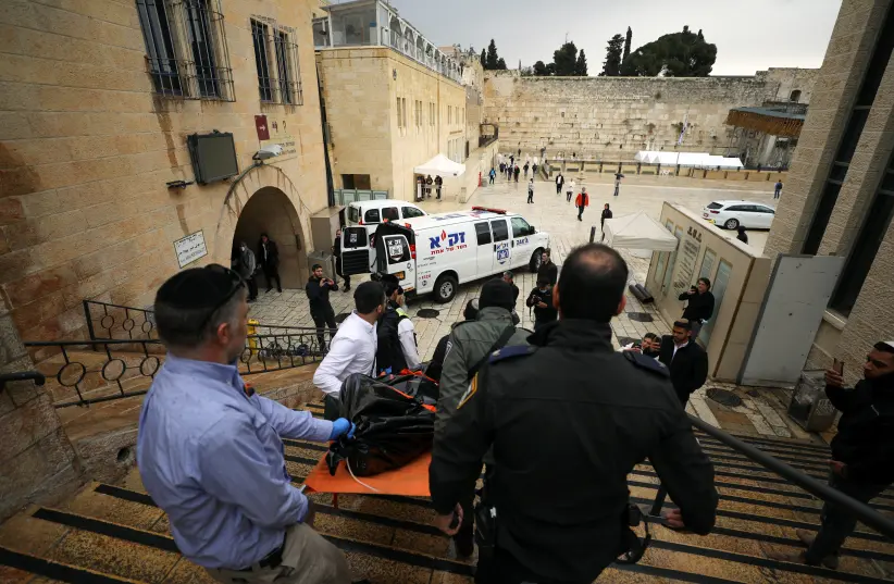 O pessoal de segurança israelense carrega um cadáver descendo as escadas que levam ao Muro das Lamentações, após um tiroteio na Cidade Velha de Jerusalém. (crédito da foto: REUTERS / AMMAR AWAD)