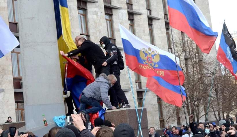 Manifestantes pró-Rússia removendo a bandeira ucraniana de um prédio em Donetsk Oblast (entidade subnacional), Ucrânia – Foto Wikipedia – CC BY-SA 3.0