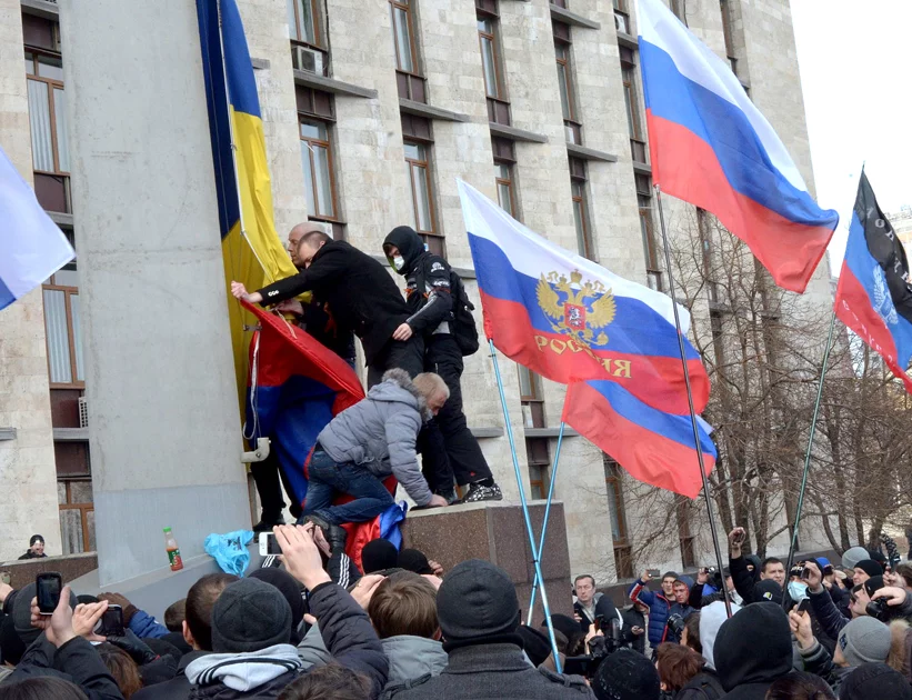 Manifestantes pró-Rússia removendo a bandeira ucraniana de um prédio em Donetsk Oblast (entidade subnacional), Ucrânia – Foto Wikipedia – CC BY-SA 3.0