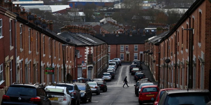 Uma pessoa atravessa uma rua repleta de casas geminadas em Blackburn, Grã-Bretanha, em 17 de janeiro de 2022. REUTERSPhil Noble